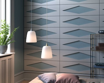 May include: Two white pendant lights hang from the ceiling in front of a wall with a geometric pattern of light blue and white diamonds. A light brown couch with two pillows and a blanket sits in front of the wall.