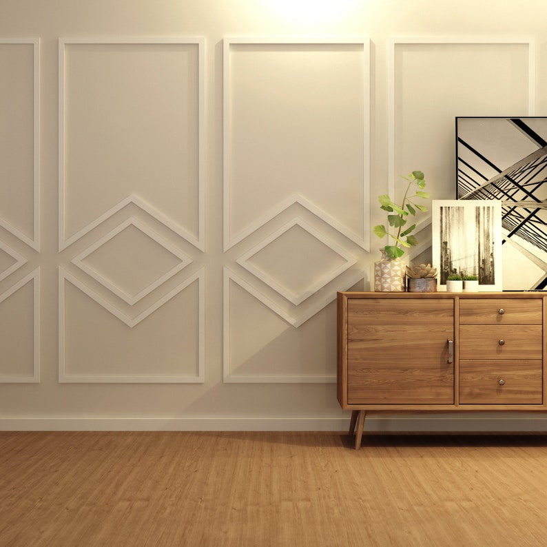 May include: A wooden cabinet with two doors and three drawers, featuring a light wood finish. The cabinet is placed against a white wall with decorative moulding. The cabinet is decorated with plants and framed artwork.