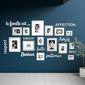 May include: A blue wall with a gallery wall of white picture frames and white wooden letters spelling out the words "la famille est... respect, amour, bonheur, belle, amis, patience, affection, rire".