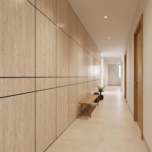 Op de afbeelding: Een lange gang met een wand bekleed met lichtbeige travertijnpanelen met donkere horizontale en verticale naden. Een houten bank staat tegen de muur, vergezeld door een kleine groene plant in een donkere ronde pot.