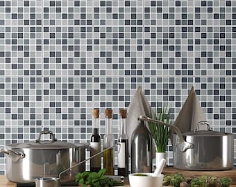 May include: A kitchen scene featuring two stainless steel pots, three glass bottles with cork stoppers, a white mortar and pestle, a small metal measuring cup, fresh herbs, and artichokes arranged on a wooden surface against a gray mosaic tile wall.