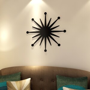 May include: A black starburst wall decor with a mid-century modern design. The starburst is made of metal and has a matte finish.