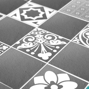 May include: A collection of square floor tiles featuring a mix of solid dark gray surfaces and tiles with white printed patterns, including geometric star shapes, intricate floral motifs, and delicate line-drawn grid designs in a matte finish.