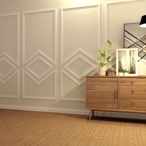 May include: A wooden dresser with two doors and three drawers. The dresser has a light wood finish and is sitting on a light brown wood floor. There are two plants in pots on top of the dresser, and a black and white photo frame is on the right side of the dresser.