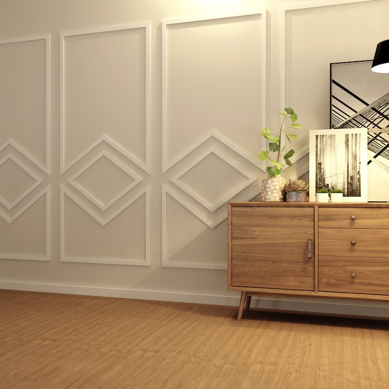 May include: A wooden dresser with two doors and three drawers. The dresser has a light wood finish and is sitting on a light brown wood floor. There are two plants in pots on top of the dresser, and a black and white photo frame is on the right side of the dresser.