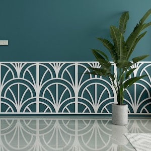 Op de afbeelding: Een teal muur met een wit decoratief paneel met een geometrisch patroon. Een plant in een pot met groene bladeren staat voor het paneel.