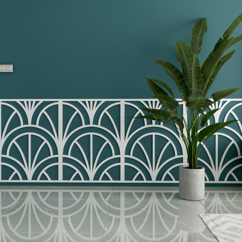 Op de afbeelding: Een teal muur met een wit decoratief paneel met een geometrisch patroon. Een plant in een pot met groene bladeren staat voor het paneel.