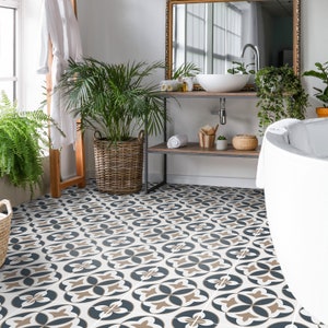 Puede incluir: Un suelo de ba&ntilde;o con baldosas cuadradas que presentan un patr&oacute;n geom&eacute;trico repetitivo en azul oscuro, beige y blanco. El dise&ntilde;o consiste en formas florales de cuatro p&eacute;talos dispuestas en cuadr&iacute;cula, creando un motivo decorativo continuo.