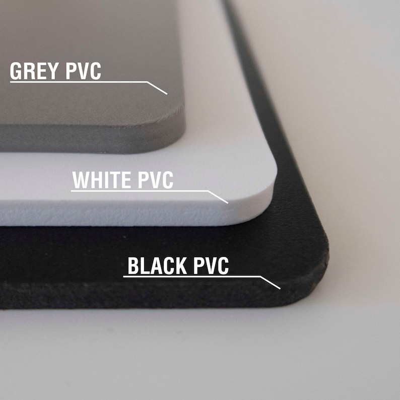 May include: Close-up of three sheets of PVC material, stacked on top of each other. The top sheet is grey, the middle sheet is white, and the bottom sheet is black. Each sheet has the text "GREY PVC", "WHITE PVC", and "BLACK PVC" printed on it.
