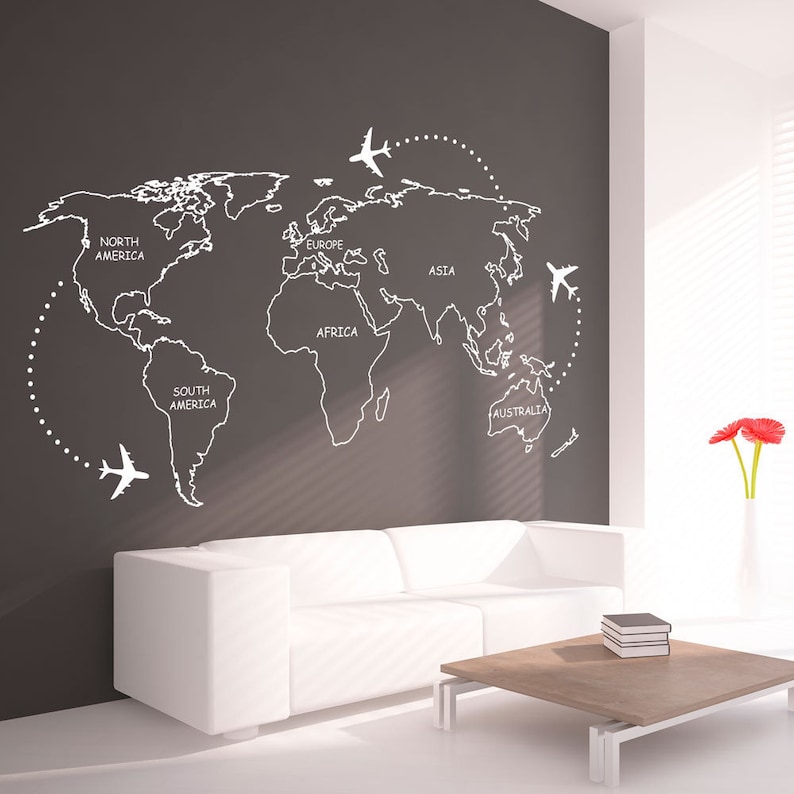 May include: A white world map with continents labeled on a gray wall. Four white airplanes are flying around the map. A white couch and a wooden coffee table are in front of the wall.