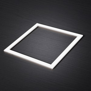May include: A white square frame on a black textured surface.