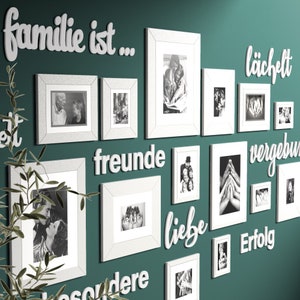 Puede incluir: Una pared verde azulada con marcos de fotos blancos y letras de madera blancas que deletrean la frase "familie ist..." y otras palabras en alem&aacute;n. Los marcos contienen fotos en blanco y negro de familias.