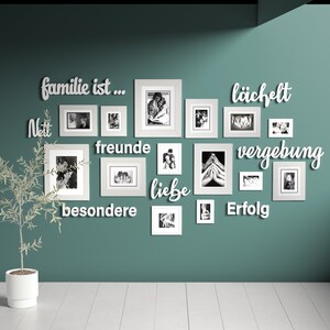 Puede incluir: Una pared turquesa con una pared de galer&iacute;a de marcos de fotos blancos. Los marcos est&aacute;n dispuestos en un patr&oacute;n aleatorio y contienen fotos en blanco y negro. La pared est&aacute; decorada con letras de madera blancas que deletrean la frase "familie ist...  neit freunde liebe besondere lachfelt vergebung erfolg".