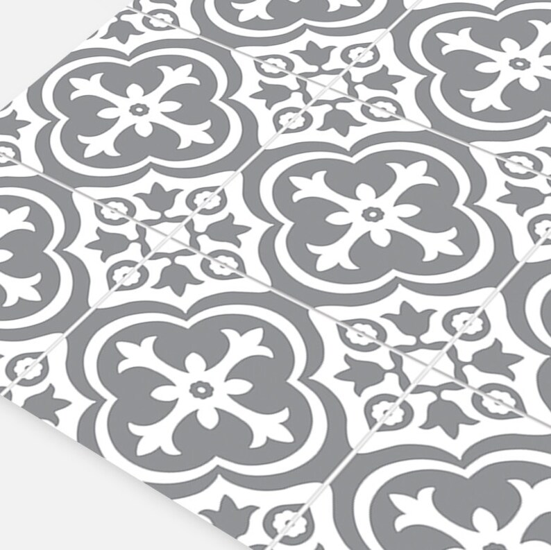 May include: A series of square tiles arranged in a grid pattern, each featuring a repeating gray and white floral-inspired quatrefoil motif. The design consists of symmetrical, curved shapes and petal-like elements centered on each individual tile.