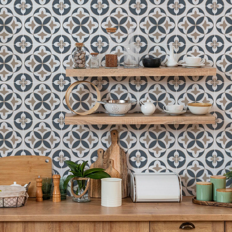 Puede incluir: Dos estantes flotantes de madera clara montados en una pared con un patr&oacute;n de azulejos geom&eacute;tricos en azul, blanco y beige. Los estantes contienen frascos de vidrio, un colador, cuencos y tazas. La encimera tiene tablas de cortar y botes.