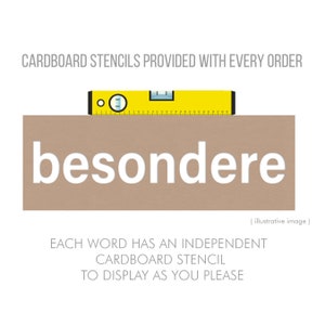 Puede incluir: Un rect&aacute;ngulo de cart&oacute;n marr&oacute;n con la palabra "besondere" impresa en blanco. La imagen incluye una herramienta de nivel amarillo y el texto "CARDBOARD STENCILS PROVIDED WITH EVERY ORDER" y "EACH WORD HAS AN INDEPENDENT CARDBOARD STENCIL TO DISPLAY AS YOU PLEASE".