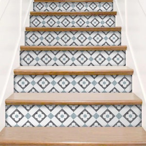 K&ouml;nnte beinhalten: Eine Treppe mit dekorativen Aufklebern f&uuml;r die Setzstufen in einem sich wiederholenden geometrischen Muster. Das Design besteht aus wei&szlig;en, dunkelgrauen und hellblauen Quadraten in einem Raster, wobei jedes Quadrat ein vierbl&auml;ttriges Blumenmotiv zeigt.
