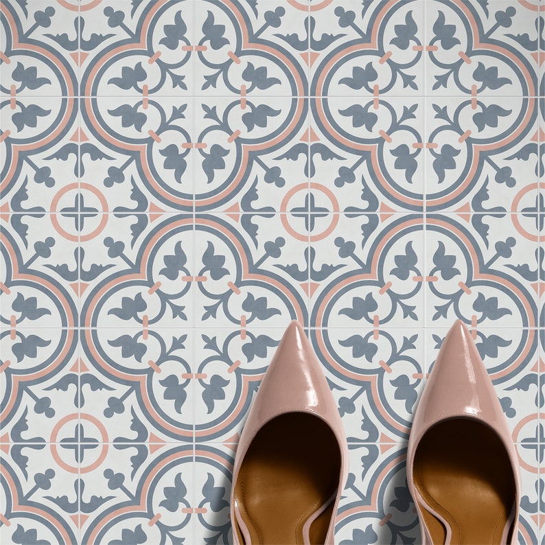 Puede incluir: Un par de zapatos de tac&oacute;n de color rosa claro brillante con punta afilada sobre un suelo de baldosas cuadradas con un patr&oacute;n repetitivo de motivos florales azul pizarra y acentos circulares rosa suave sobre fondo blanco.