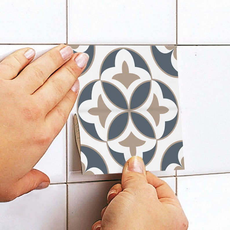Puede incluir: Un adhesivo cuadrado para azulejos con un patr&oacute;n geom&eacute;trico repetitivo en tonos azul pizarra, beige y blanco. El dise&ntilde;o consta de cuatro formas de p&eacute;talos entrelazados dispuestos en un motivo floral sim&eacute;trico sobre un fondo blanco.