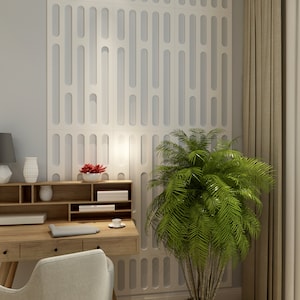 May include: A home office setup featuring a light wood desk with drawers, a gray chair, and a white wall with a repeating vertical design. A green plant and a gray lamp add to the decor. A small white vase and a red flower arrangement are on the desk.