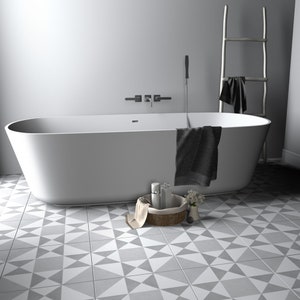May include: A white freestanding oval bathtub with a dark gray towel draped over the side. A woven basket containing two bottles and a small vase with flowers sits on the floor. A metal ladder towel rack stands nearby against the wall.