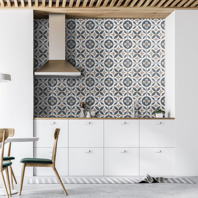 Puede incluir: Un salpicadero de cocina con azulejos cuadrados que presentan un patr&oacute;n geom&eacute;trico repetitivo en tonos azul oscuro, beige y blanco. Los azulejos est&aacute;n dispuestos en cuadr&iacute;cula detr&aacute;s de una campana extractora de acero y armarios blancos.