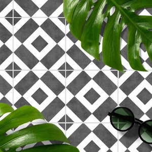 May include: A set of square tiles featuring a geometric pattern of dark gray squares centered within white diamond outlines. The tiles are arranged in a grid, accented by two large, vibrant green monstera leaves and a pair of round black sunglasses.