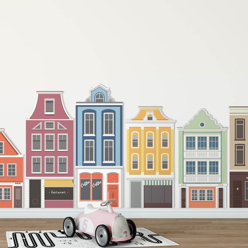 May include: A colorful row of toy houses with different storefront signs, including "Restaurant" and "Coffee". A pink toy car with a number 5 on the side is in front of the houses.