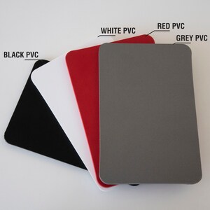 Peut inclure: Une pile de feuilles rectangulaires en PVC noir, blanc, rouge et gris. Le texte indique chaque couleur : "BLACK PVC", "WHITE PVC", "RED PVC" et "GREY PVC". Les feuilles ont des coins arrondis.