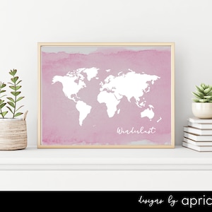 May include: A pink watercolor print with a white outline of the world map and the word "Wanderlust" written in white script. The print is framed in a light wood frame and is sitting on a white shelf.