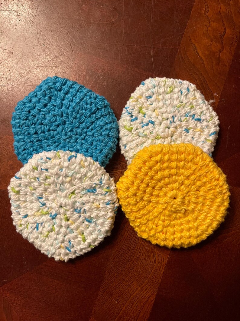 May include: Four crocheted dishcloths in different colors: blue, white with blue and green flecks, white with green and blue flecks, and yellow.