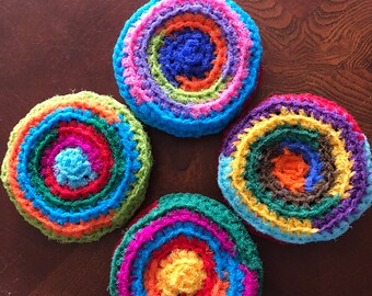 May include: Four colorful crocheted circles with concentric rings of different colors. The circles are made of yarn in shades of pink, blue, green, orange, yellow, and brown.