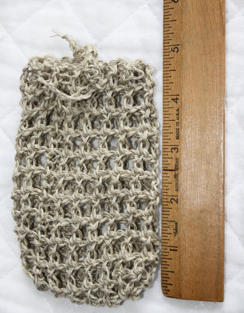 May include: A beige, crocheted, mesh bag with a drawstring closure. The bag is about 4 inches tall and 2 inches wide.