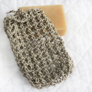 May include: A beige crocheted soap sack with a bar of soap inside. The soap sack is made of natural fibers and is designed to help create a lather when used with soap.