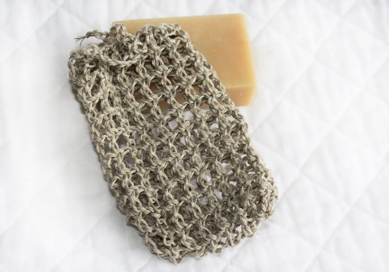 May include: A beige crocheted soap sack with a bar of soap inside. The soap sack is made of natural fibers and is designed to help create a lather when used with soap.