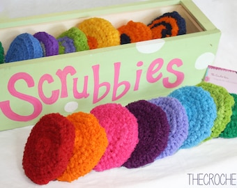May include: A wooden box with the word "Scrubbies" painted on the front. The box is filled with colorful crocheted scrubbies in a rainbow of colors.