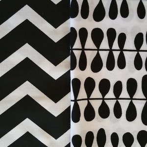 May include: Black and white fabric with two different patterns. One side has a chevron pattern and the other side has a repeating teardrop pattern.