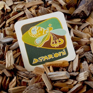 May include: A brown and green square coaster with a stylized bee design and the text "D.FARONI" in yellow letters.