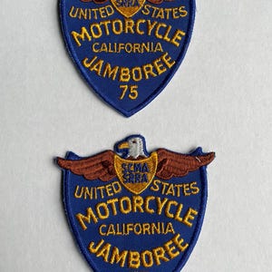 May include: Two blue and gold embroidered patches with an eagle design. The patches read "United States Motorcycle California Jamboree 75" and have a small shield with the text "SCMA SRRA" in the center.