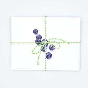May include: A white card with a green and white twine bow tied around it. The card has a watercolour painting of blueberries on it.