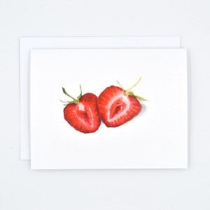 May include: Two halves of a red strawberry, cut in half, with the inside of the fruit showing. The strawberries are on a white background.