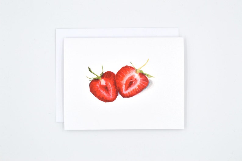 May include: Two halves of a red strawberry, cut in half, with the inside of the fruit showing. The strawberries are on a white background.
