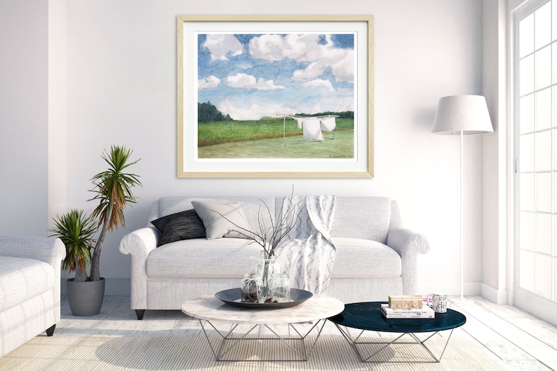 May include: A framed watercolor painting of a green field with white laundry hanging on a clothesline. The sky is blue with white clouds.