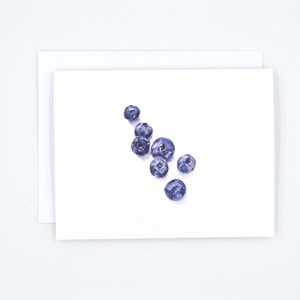 May include: A watercolour painting of blueberries on a white background. The blueberries are arranged in a loose cluster, with some overlapping.