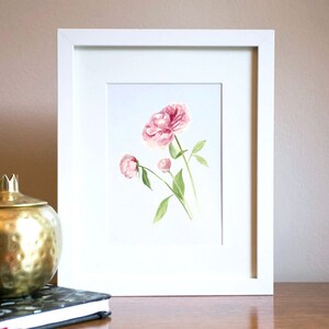 May include: A framed watercolour painting of pink peonies with green stems and leaves.