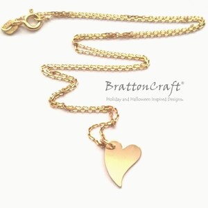 May include: A gold chain necklace with a heart pendant. The chain is a delicate box chain and the heart is a simple, flat design. The necklace is a simple and elegant piece of jewelry.