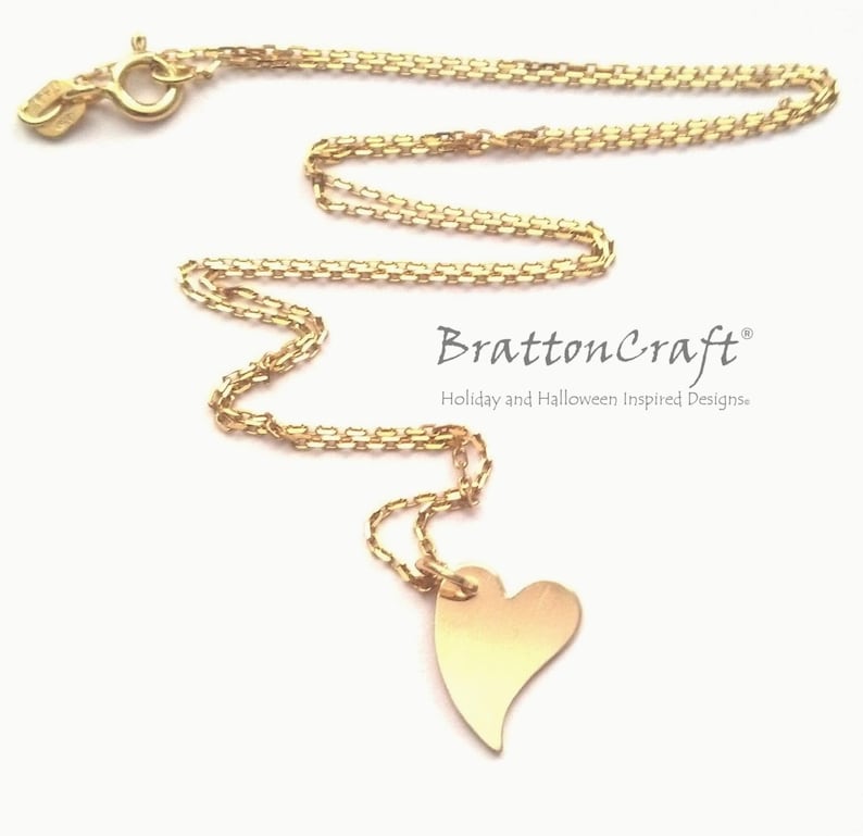 May include: A gold chain necklace with a heart pendant. The chain is a delicate box chain and the heart is a simple, flat design. The necklace is a simple and elegant piece of jewelry.