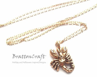 Könnte beinhalten: Goldkette mit einem goldenen Skorpion-Anhänger. Der Anhänger ist detailliert und hat eine strukturierte Oberfläche. Die Kette ist 45,7 cm lang.