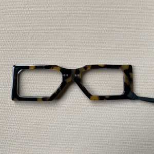May include: A pair of tortoiseshell reading glasses with a black cord.