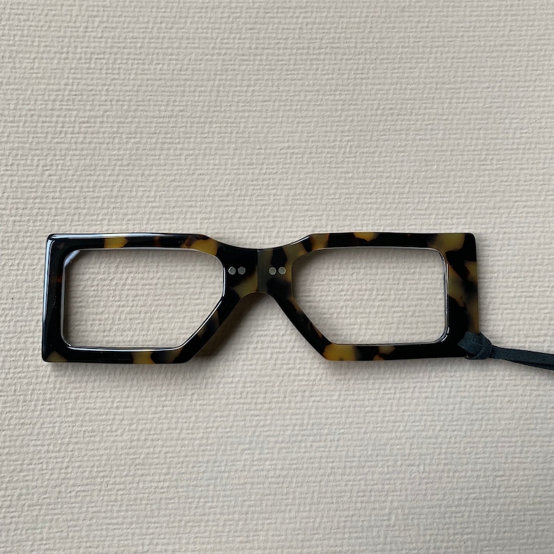 May include: A pair of tortoiseshell reading glasses with a black cord.
